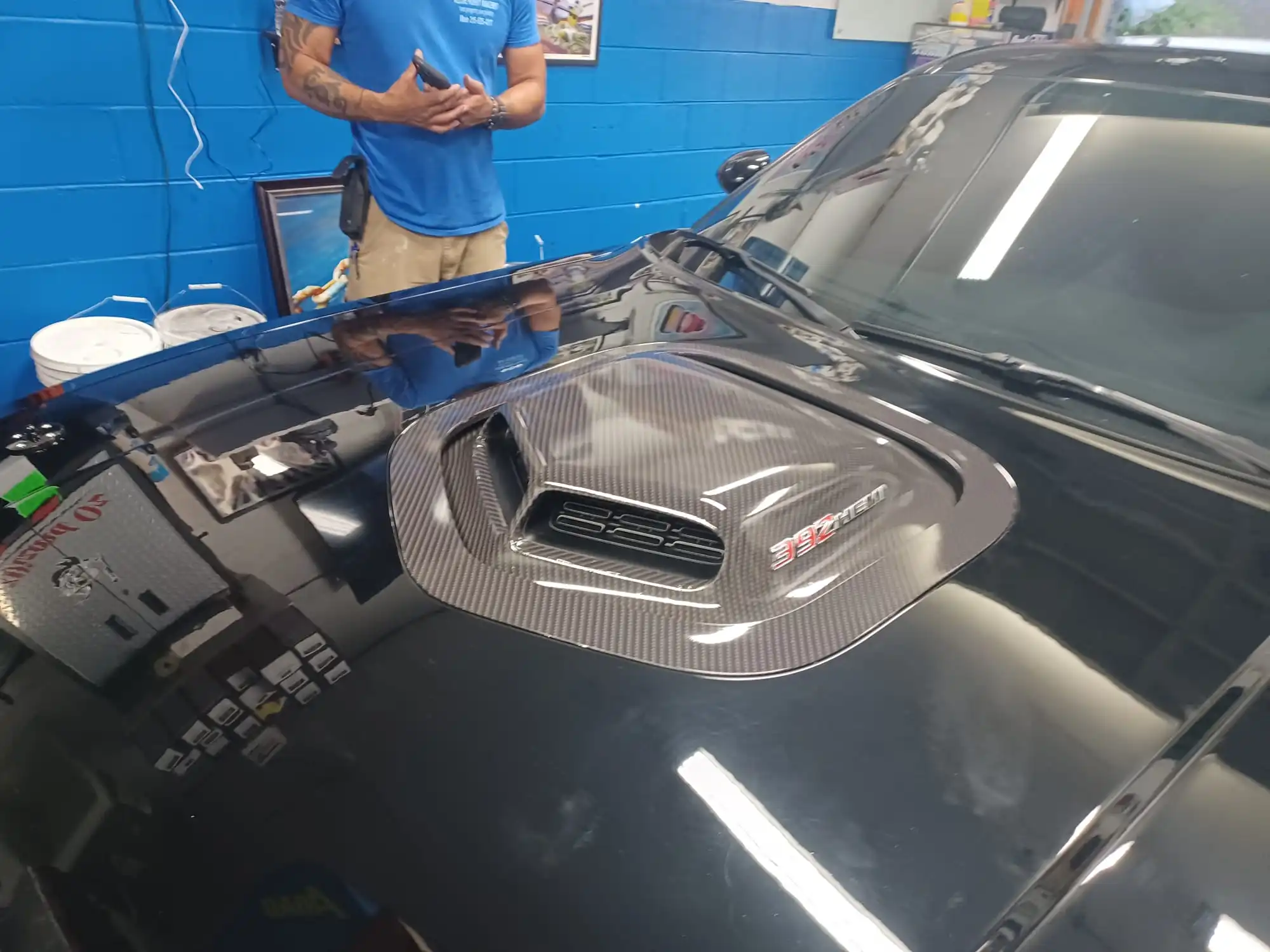 Carbon-fiber-style vinyl being installed on a vehicle hood